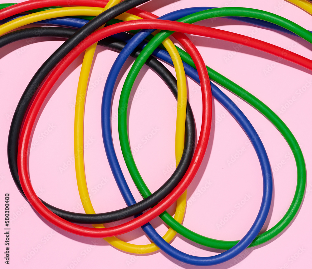 Multicolored rubber tubes on a pink background, top view Multicolored rubber tubes on a pink background, top view