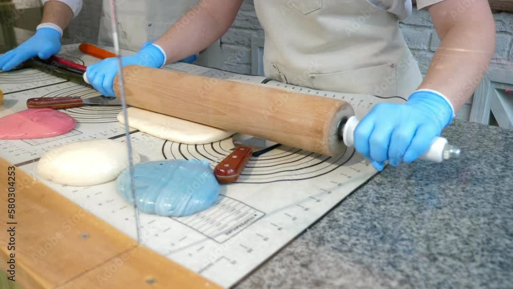 Close-up of two pastry chefs making handmade lollipops in a professional pastry shop, they roll out soft caramel with a rolling pin and hands. Close-up of two pastry chefs making handmade lollipops in a professional pastry shop, they roll out soft caramel with a rolling pin and hands.