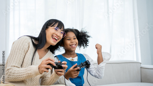 African american kid , baby sitter and cute little girl having fun together, playing video games, sitting on the couch. Leisure activities, babysitting concept. photo