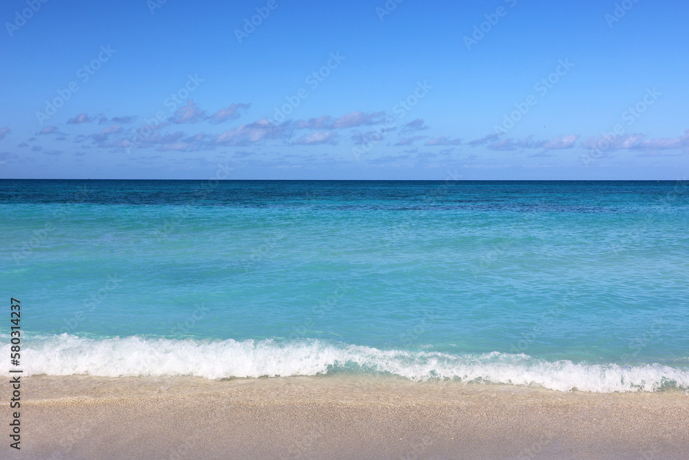Tropical beach with white sand on a ocean, view to azure waves and sky with clouds. Caribbean coast, Background for holidays on a paradise nature Tropical beach with white sand on a ocean, view to azure waves and sky with clouds. Caribbean coast, Background for holidays on a paradise nature