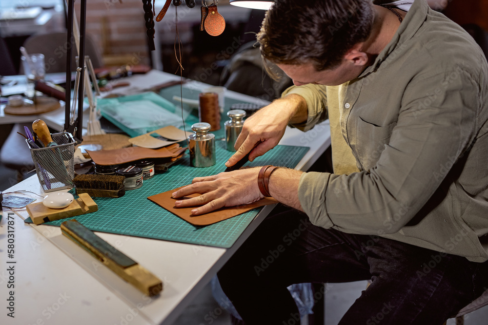 young active man sewing leather wallet, close up side view shot, guy prepare material for sewing, stitching young active man sewing leather wallet, close up side view shot, guy prepare material for sewing, stitching