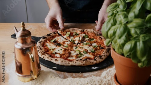 Young Chef Grabbing a slice of homemade sourdough vegan bbq chicken pizza baked in a gas-fired pizza oven.