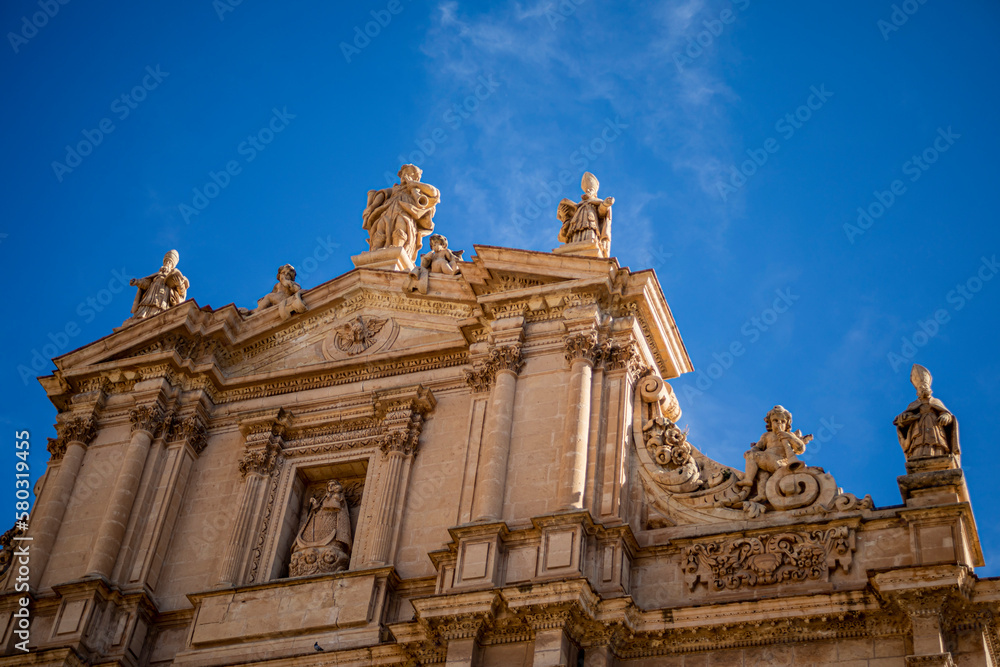 Fototapeta premium Upper part of the monumental facade of the Collegiate Church of San Patricio in Renaissance style and profusely decorated with sculptures from Lorca, Murcia, Spain