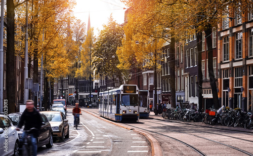 Amsterdam, Netherlands. Street view, Modern tram, public transport moving by Autumn evening sunny day. Bicycle on the road