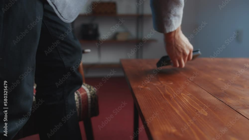 A man with drawings and a smartphone sits in a chair and lays everything out on a coffee table, after which he examines the drawings. Close-up on hands and blueprints A man with drawings and a smartphone sits in a chair and lays everything out on a coffee table, after which he examines the drawings. Close-up on hands and blueprints