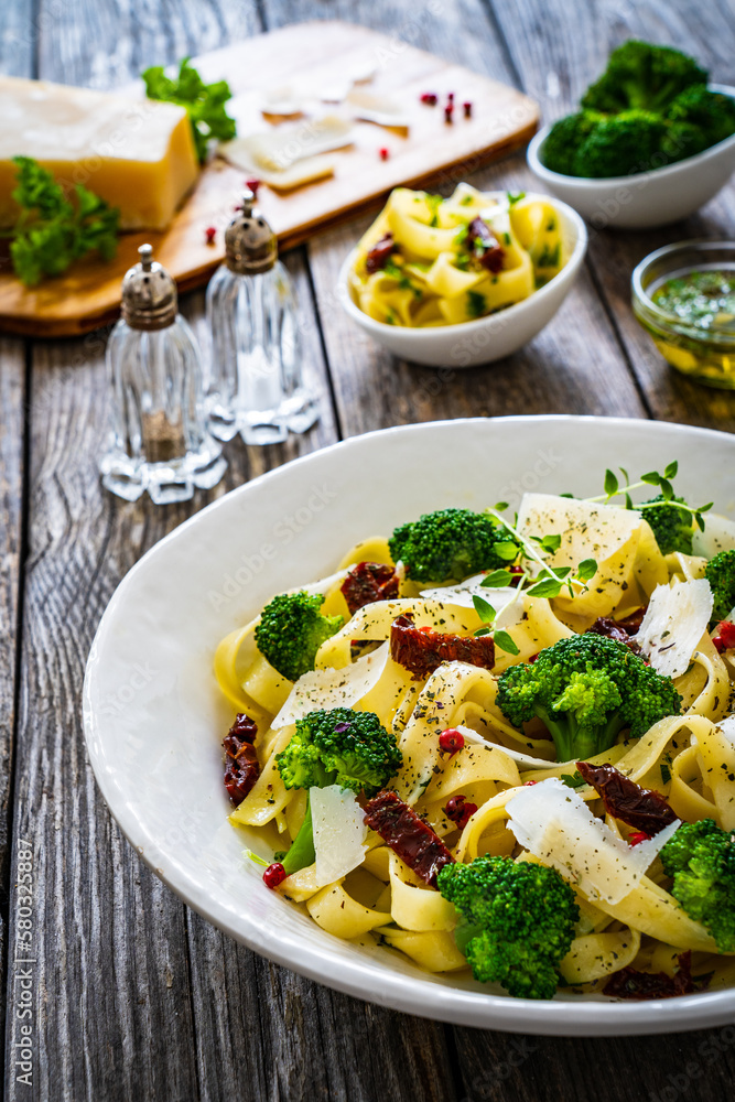 Pasta with broccoli, parmesan and sun dried tomatoes on wooden table
Pasta with broccoli, parmesan and sun dried tomatoes on wooden table