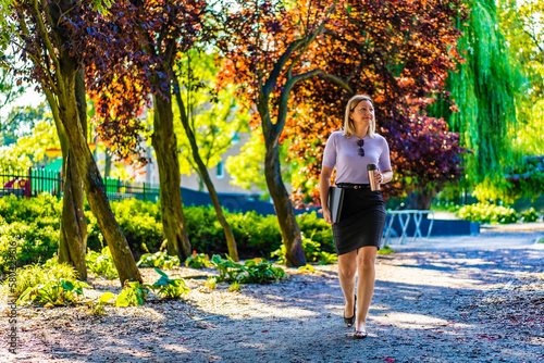 Coffee break - beautiful woman walking in city park
