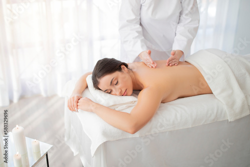 Attractive young indian woman receiving body massage in spa salon