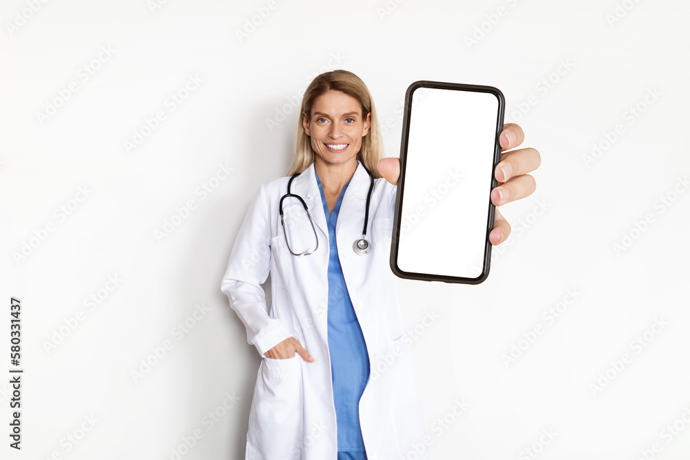 Beautiful Doctor Woman Wearing White Coat Showing Big Smartphone With Blank Screen Beautiful Doctor Woman Wearing White Coat Showing Big Smartphone With Blank Screen