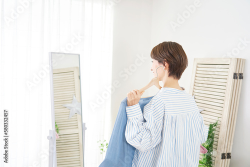 家で鏡を見て洋服を選ぶ女性