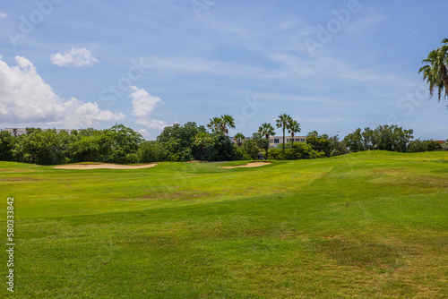 Beautiful view of green grass golf field on background blue sky on Aruba island. 