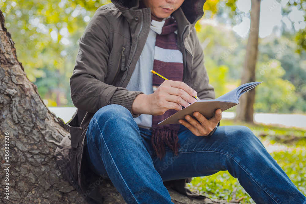 Asian man sitting and writing for a tree Asian man sitting and writing for a tree