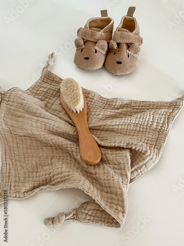 a beige muslin scarf, brown shoes with a muzzle and ears and a children's hair brush lie on a light background