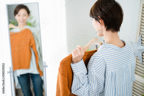 鏡の前で服選びをしている若い女性 ファッションイメージ