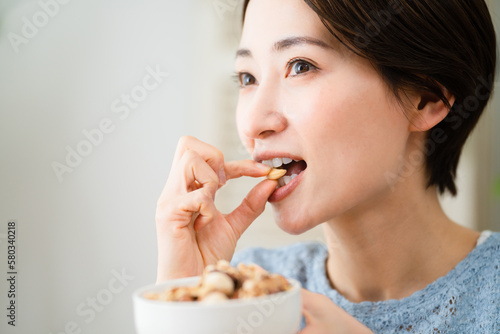 ミックスナッツを食べる若い女性 飲食イメージ