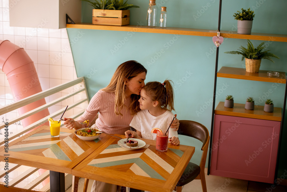 Mother and daughter having a breakfast with fresh squeezed juices in the cafe Mother and daughter having a breakfast with fresh squeezed juices in the cafe