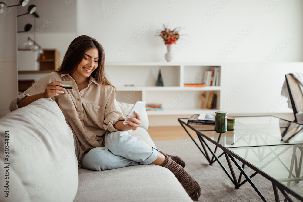 Cheerful young asian woman with credit card typing on smartphone, makes order remotely Cheerful young asian woman with credit card typing on smartphone, makes order remotely