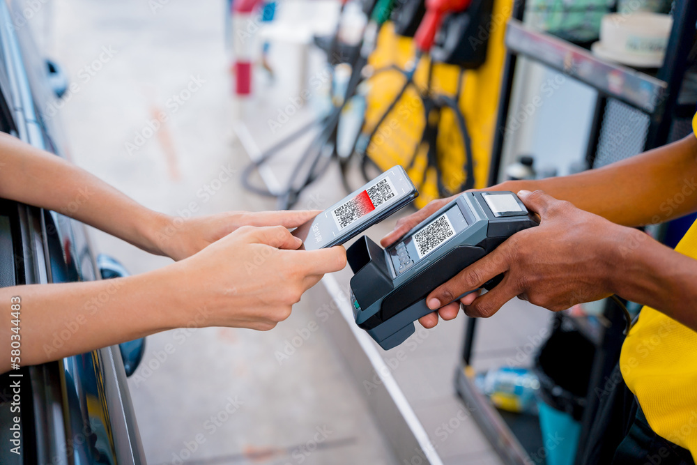 Woman using contactless payment by mobile phone with QR code at car filling station Woman using contactless payment by mobile phone with QR code at car filling station