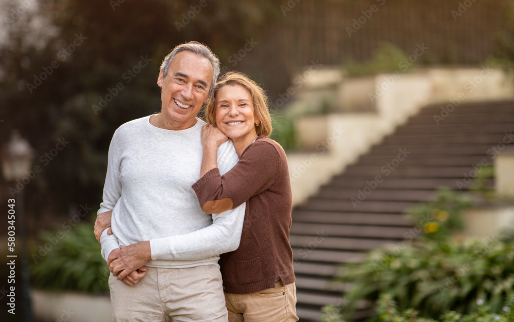 Happy Senior Couple Embracing Smiling To Camera Standing In Park Happy Senior Couple Embracing Smiling To Camera Standing In Park