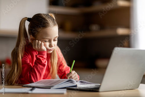 Little cute girl feeling tired and sleepy while doing her homework