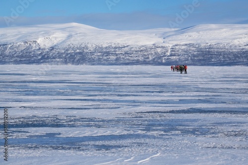 Silhouettes of tourists on snowshoes on lake Torneträsk (Tornestrask) around Abisko National Park (Abisko nationalpark) in winter scenery. Sweden, Arctic Circle, Swedish Lapland