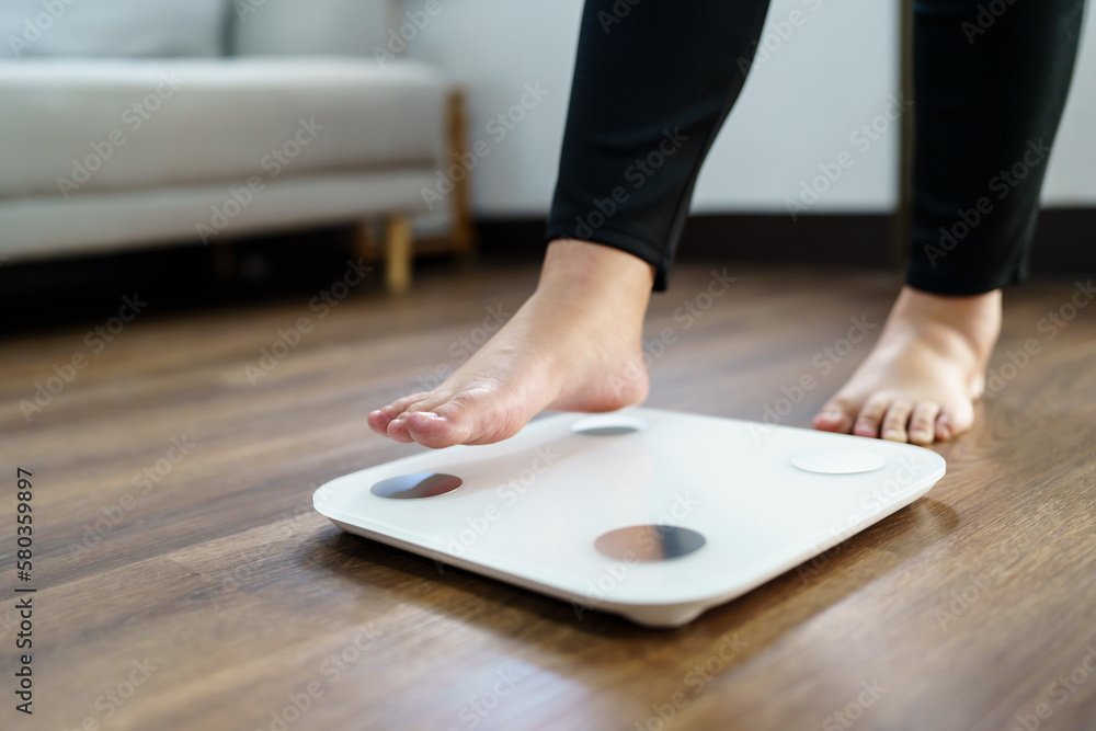 Fototapeta premium Lose weight. Fat diet and scale feet standing on electronic scales for weight control. Measurement instrument in kilogram for diet