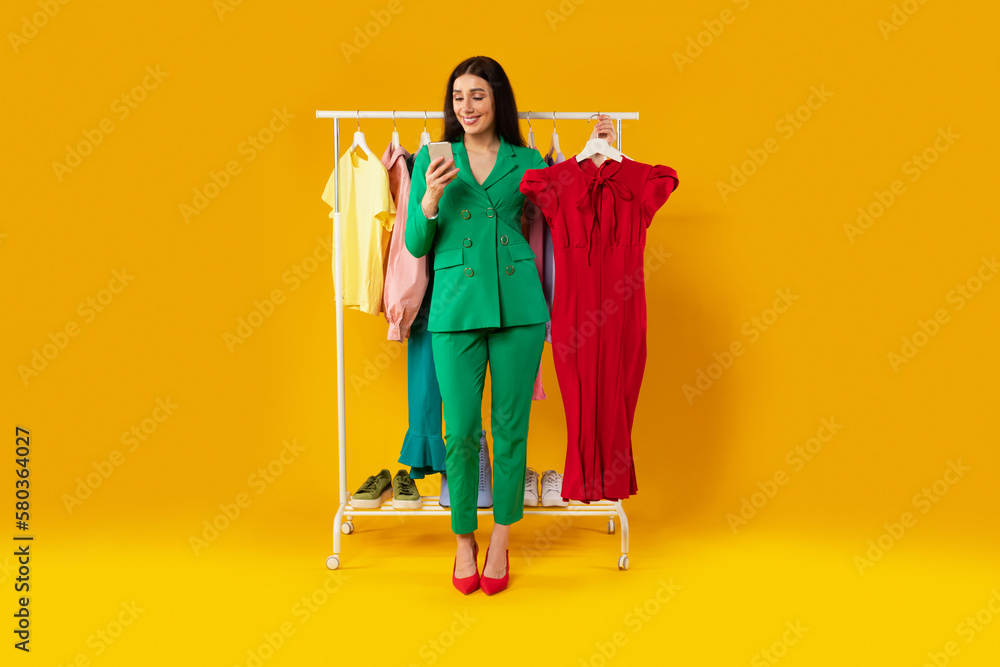 App for online shopping. Young european lady using cellphone and holding  dress, ordering clothes online in mobile app Stock Photo | Adobe Stock