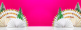 White table with paper fans and new year trees on magenta background with space for product presentation. Christmas and New Year holiday background, mockup banner for display of advertising products