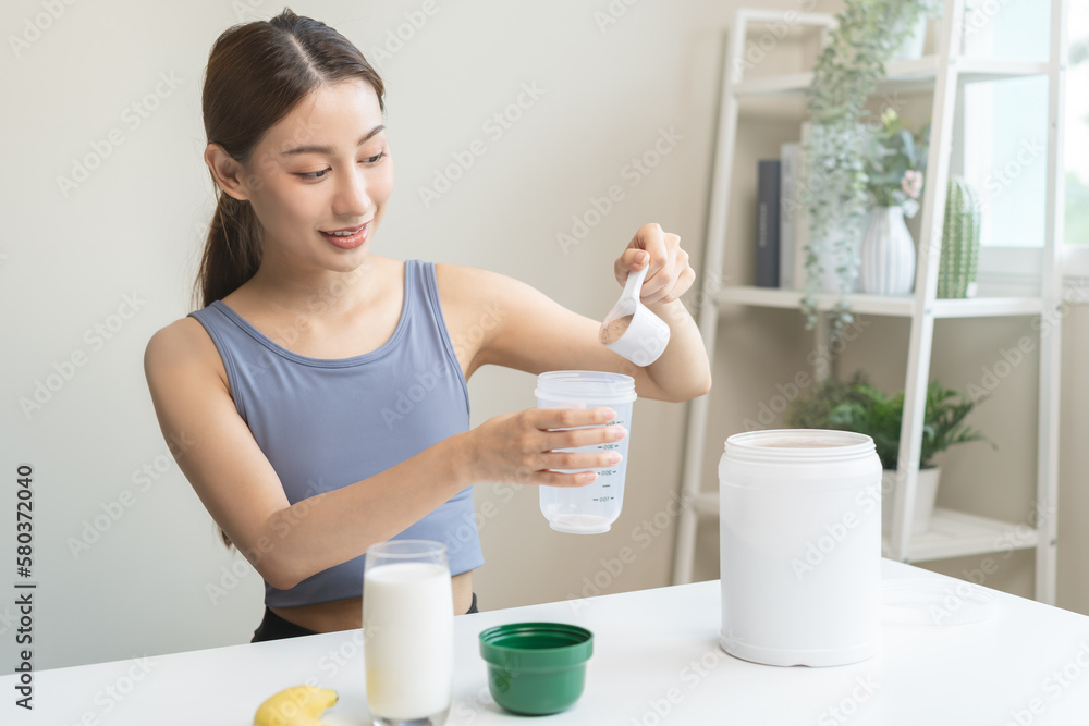 Diet meal replacement for weight loss, smile asian young woman, girl in sportswear, hand in holding scoop making protein shake, drink supplement for muscle after workout at home. Healthy body care. Diet meal replacement for weight loss, smile asian young woman, girl in sportswear, hand in holding scoop making protein shake, drink supplement for muscle after workout at home. Healthy body care.