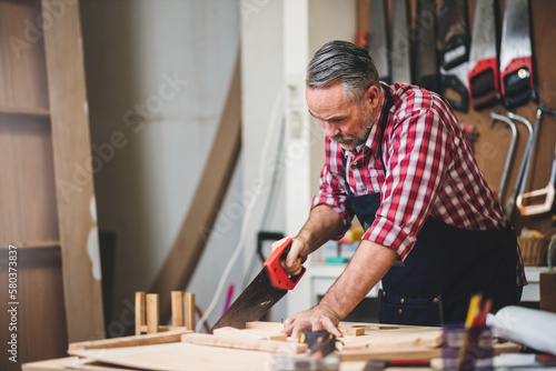 Professional senior cauasian man working woodworking handmade with tools in wood workshop, Timber factory industry.