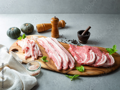 Various cuts of pork meat and spices on a cutting board photo