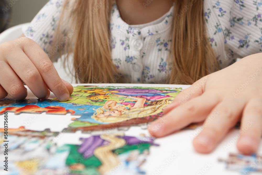 Fototapeta premium Little child picks up picture from pieces of puzzles