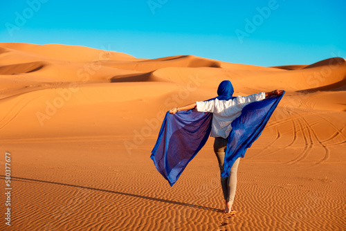 Beautiful caucasian woman posing in blue waving textile in the sahara desert photo