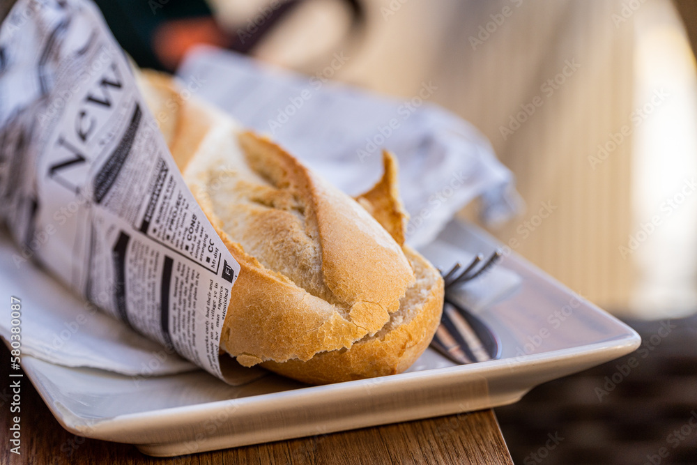 Crispy bread sandwich wrapped in newspaper.