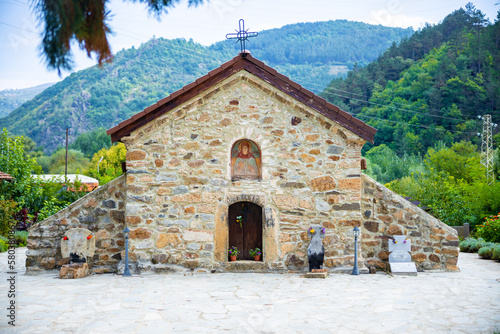 Small beautiful church in Bulgaria in the mountain. Green hills with forests and trees behind it. High quality photo
