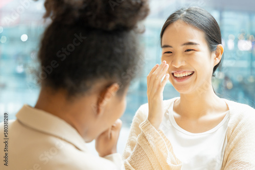 Asian woman talking fluently  laughing with her African friend  concept image of good command in foreign language