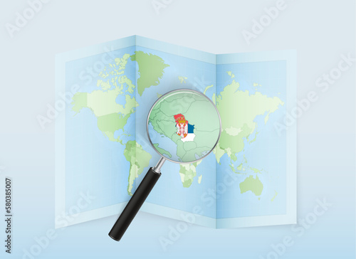 A folded world map with a magnifying lens pointing towards Serbia. Map and flag of Italy in loupe.