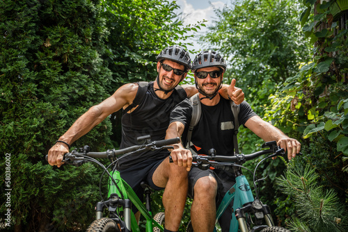 portrait of two men friends wear protective helmet during bike ride
