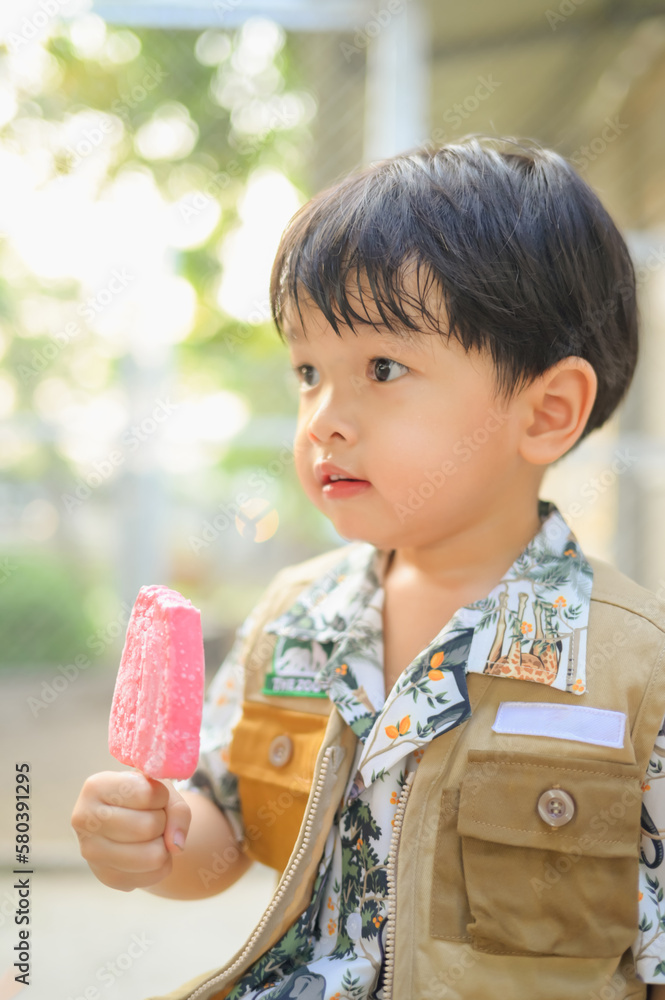Asian boy eating ice cream in park Asian boy eating ice cream in park