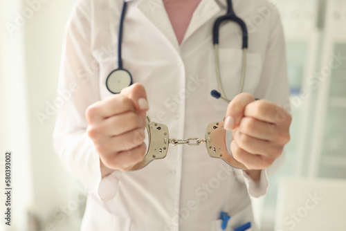 Obraz na płótnie Doctor with stethoscope in handcuffs close-up. Nurse with metal handcuffs on her hands. w salonie