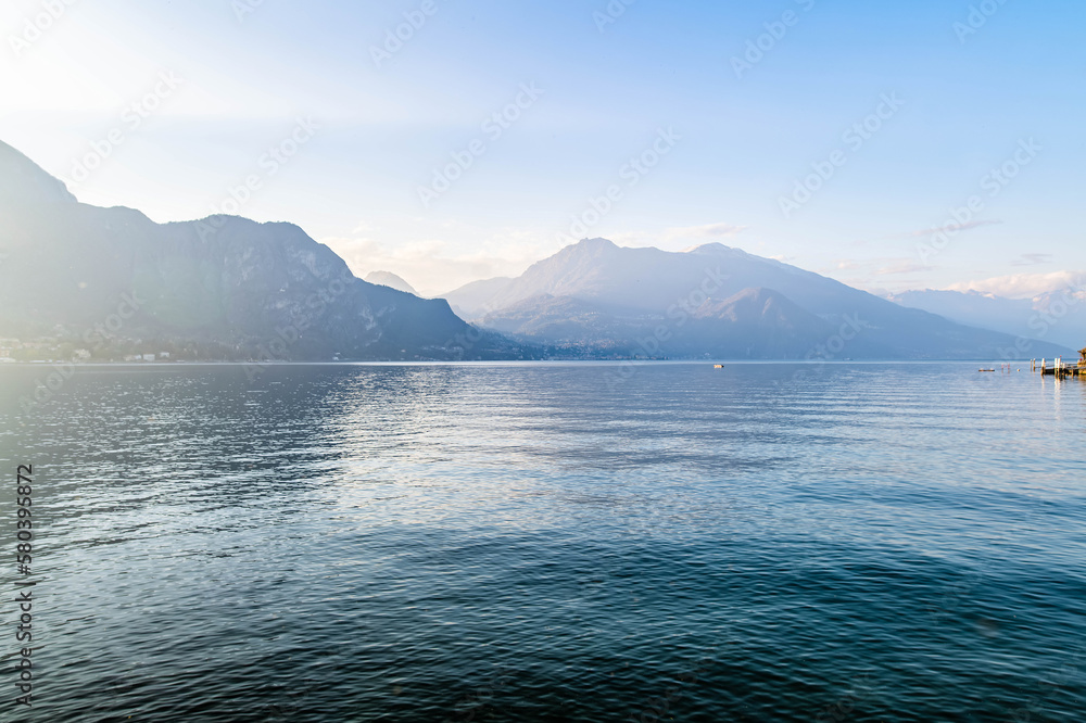 Beautiful aerial view of the famous Como Lake on sunny summer day. Clouds reflecting in calm waters of the lake with Alp mountains on the background.