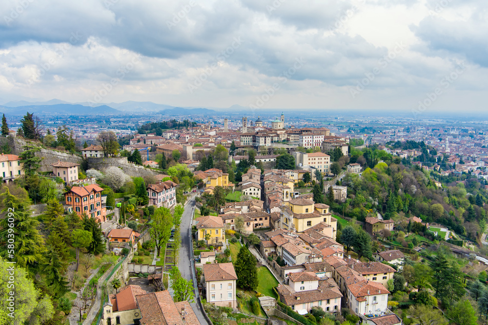 Naklejka premium Scenic aerial view of Bergamo city. Flying over Citta Alta, town's upper district, known by cobblestone streets and encircled by Venetian walls. Bergamo, Lombardy, Italy.