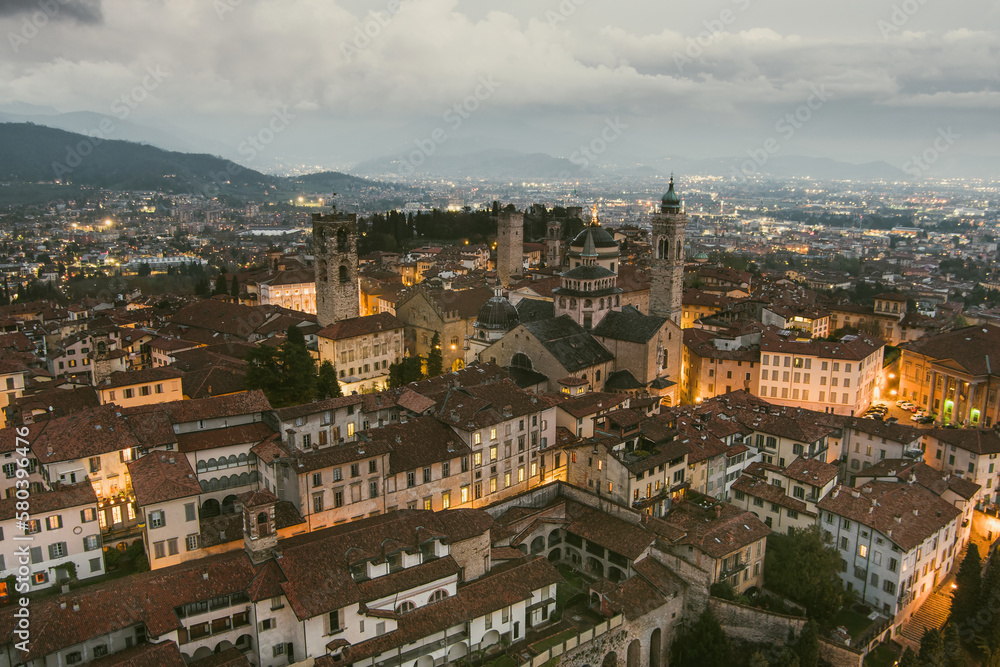 Scenic aerial view of Bergamo city northeast of Milan, on cloudy evening. Flying over Citta Alta, town's upper district encircled by Venetian walls. Bergamo, Italy.