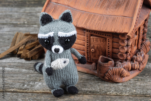 knitted raccoon with a fish in his hands on a wooden table photo