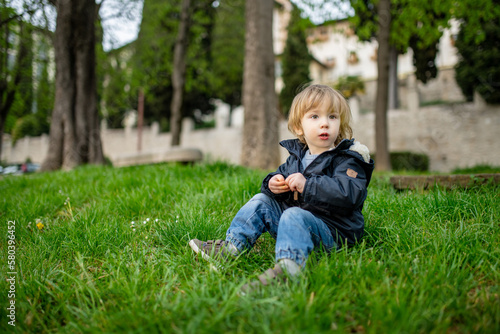 Cute toddler boy playing in the grass in Bergamo. Little child having fun exploring in Citta Alta, upper district of Bergamo. Bergamo, Italy.