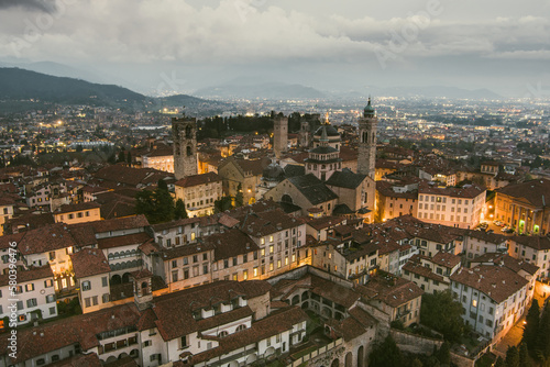Scenic aerial view of Bergamo city northeast of Milan  on cloudy evening. Flying over Citta Alta  town s upper district encircled by Venetian walls. Bergamo  Italy.