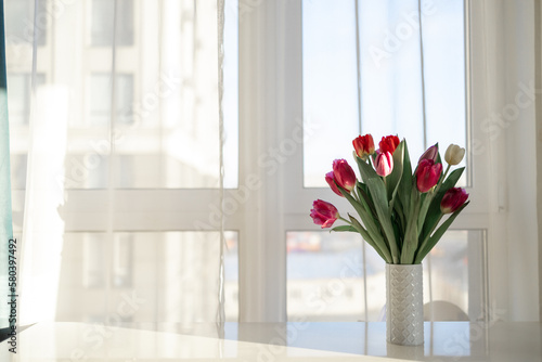 beautiful tulips in vase on white windowsill