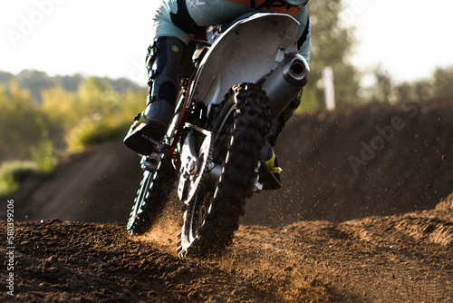 A young man, a man, an athlete, driving a motocross motorcycle in the blur, on a dirt track. Movement, blur, slow-motion, field. Evening, sunset.