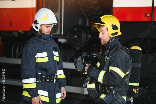 Portrait of two heroic fireman in protective suit and helmet.