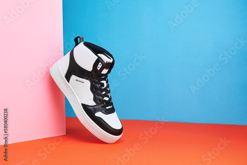Black and white sneakers on a colored background. Stylish style footwear for advertising a shoe store. Hype sneaker
